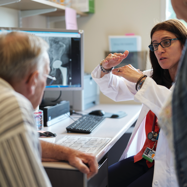 Image of a female doctor speaking to a patient while sitting at her desk.